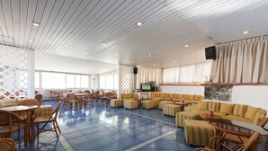 A spacious indoor area with a blue tiled floor, wooden ceiling, and a mix of seating arrangements including sofas and chairs. - Hotel Terme Colella (Forio)