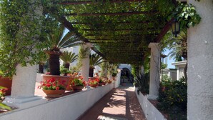A covered walkway with potted plants and a tiled floor. - Hotel Terme Colella (Forio)