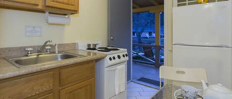 A kitchen with wooden cabinets, a stainless steel sink, a stove, and a refrigerator.