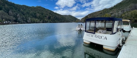 Un bateau nommé NEW ORCA a accosté à un quai d’où l’on pouvait admirer un lac et, au loin, des collines boisées.