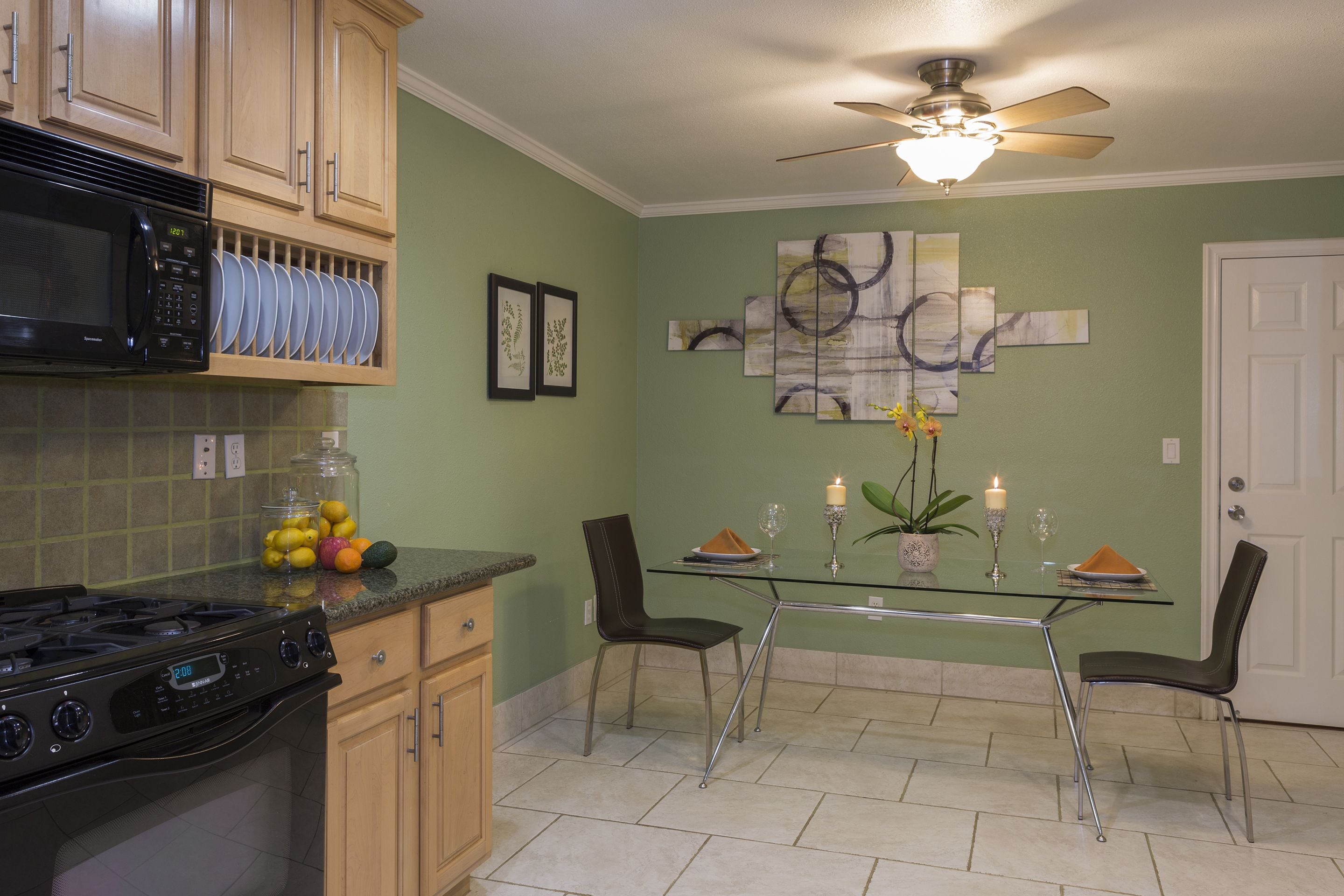 A kitchen with a gas stove, microwave, and a glass dining table with chairs.