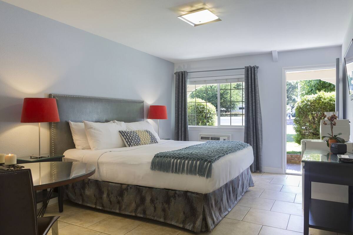 A neatly arranged bedroom with a bed, bedside tables, and a window with curtains.
