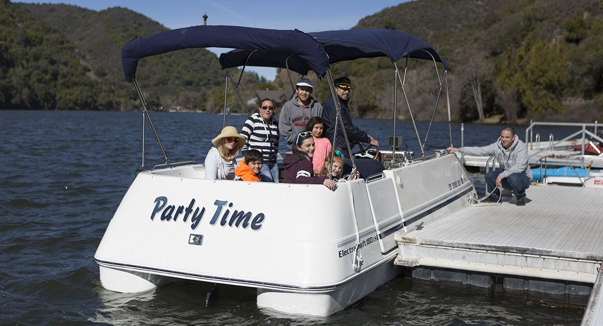 Katettu kannella varustettu vene, jonka kylkeen oli maalattu teksti ”Party Time”, oli ankkuroitu laituriin.