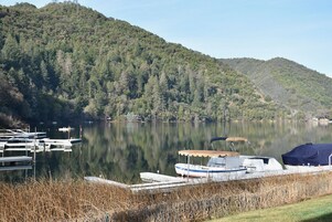 A calm lake with docked boats, surrounded by forested hills.