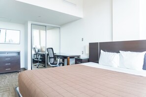 Una habitación de hotel con cama, escritorio, silla y armario.