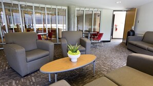 A modern lounge area with grey sofas, a wooden coffee table, and a potted plant. - University of Calgary Accommodations & Events (Calgary)
