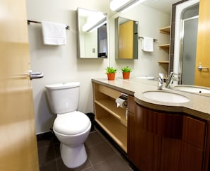 Une salle de bain moderne avec des toilettes, un lavabo et un miroir. Deux plantes en pot sont posées sur le meuble-lavabo.