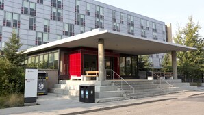 A modern building with a covered entrance, steps leading up to the entrance, and a bench outside. - University of Calgary Accommodations & Events (Calgary)