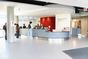 A reception desk with a red curtain backdrop, a sign for the Campus Service Centre, and a pillar with an arrow sign. - University of Calgary Accommodations & Events (Calgary)
