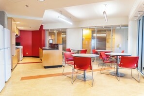 A modern dining area with red chairs, a central bar, and a kitchen in the background. - University of Calgary Accommodations & Events (Calgary)