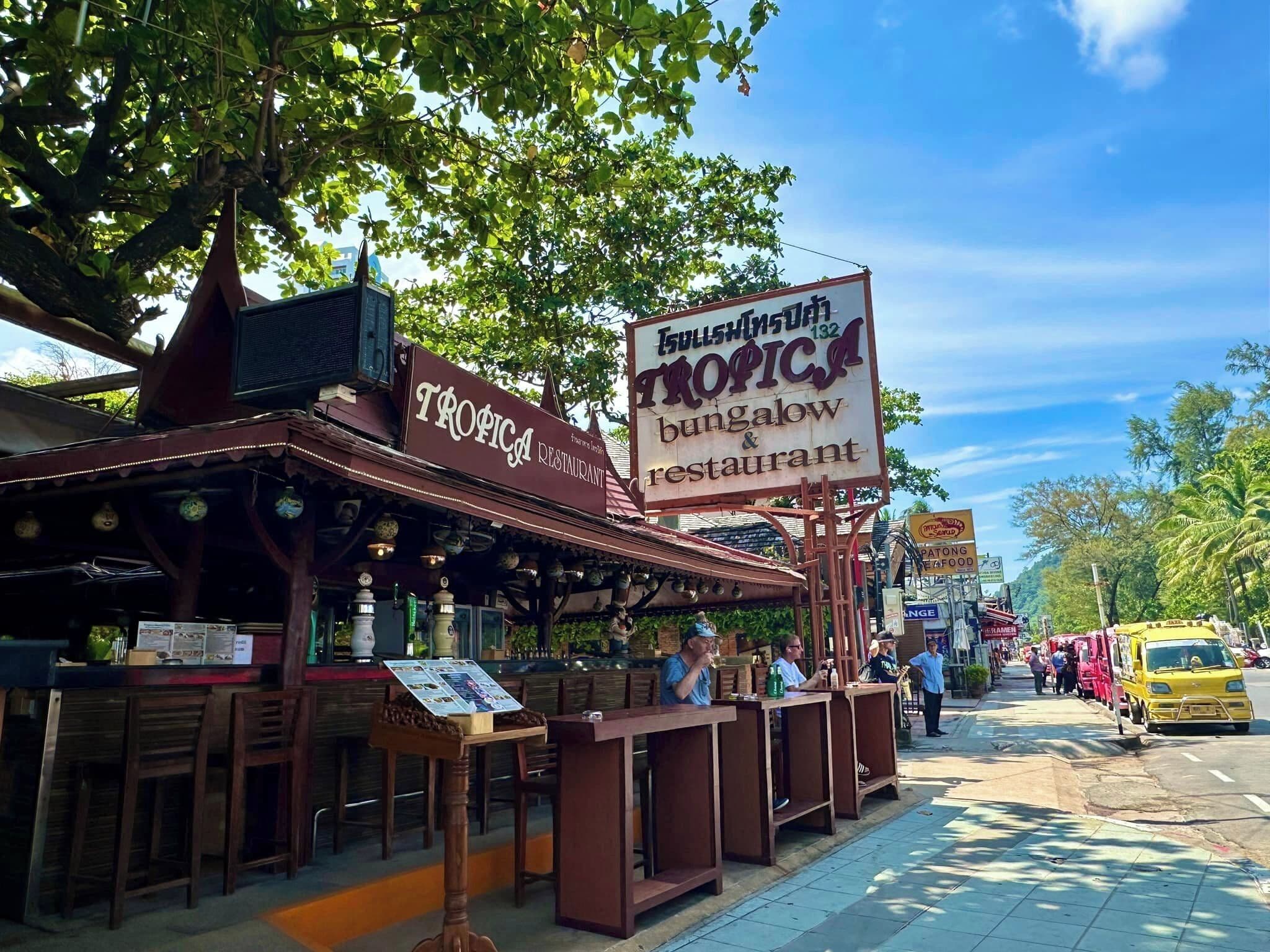 A restaurant named Tropica with outdoor seating and a sign advertising a bungalows and restaurant.