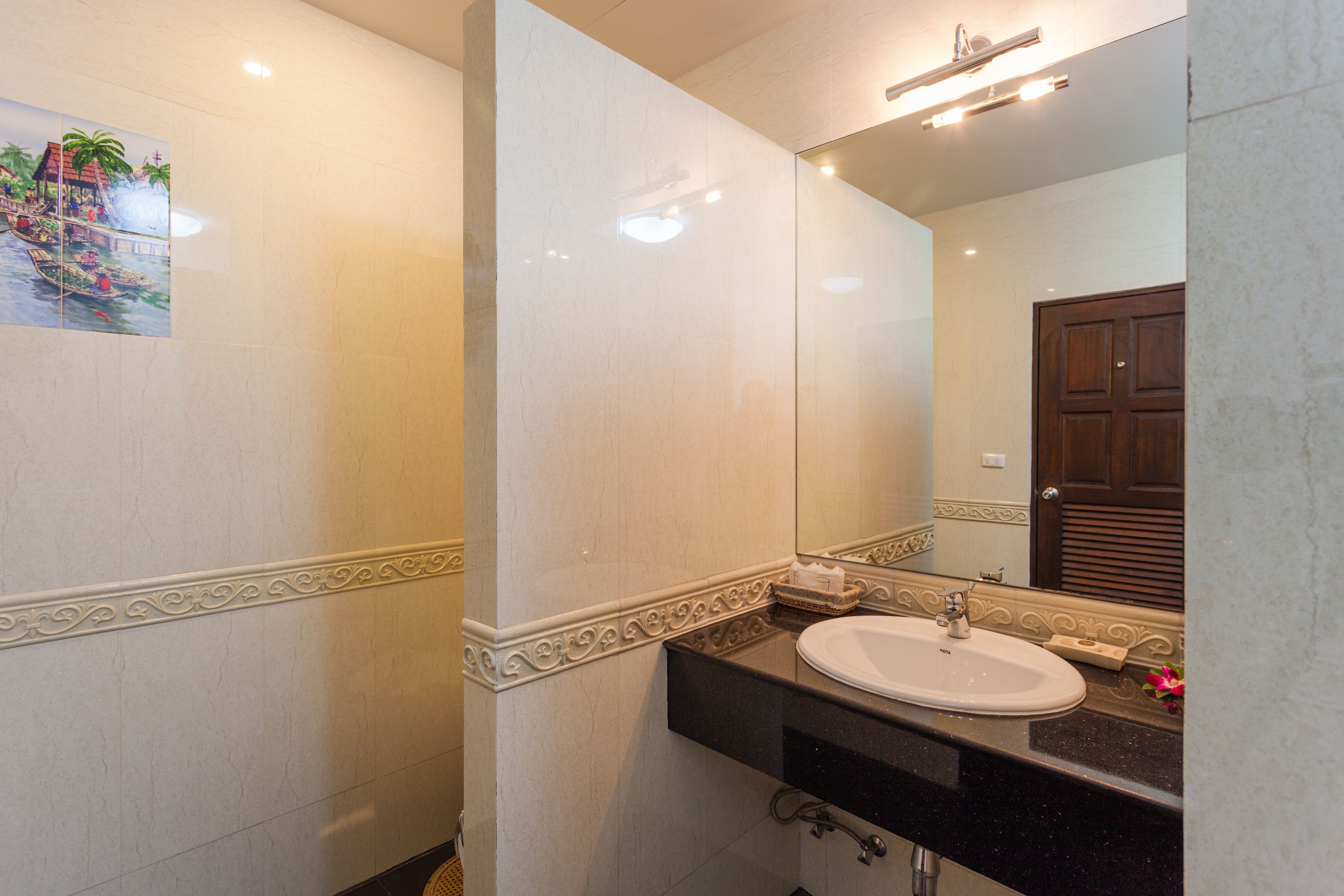 A bathroom with a white sink, a mirror, and a decorative tile border.