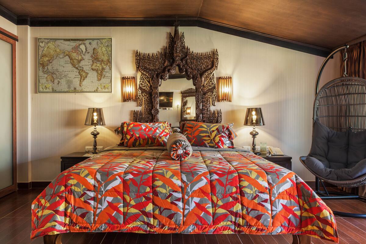 A bedroom with a large bed, a map on the wall, and a decorative mirror.