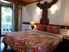 Una habitación de hotel con cama, mesita de noche, lámpara e iluminación empotrada en la pared.