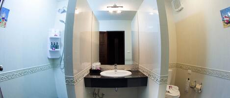 A bathroom with a white sink, dark floor tiles, a mirror, and a toilet.