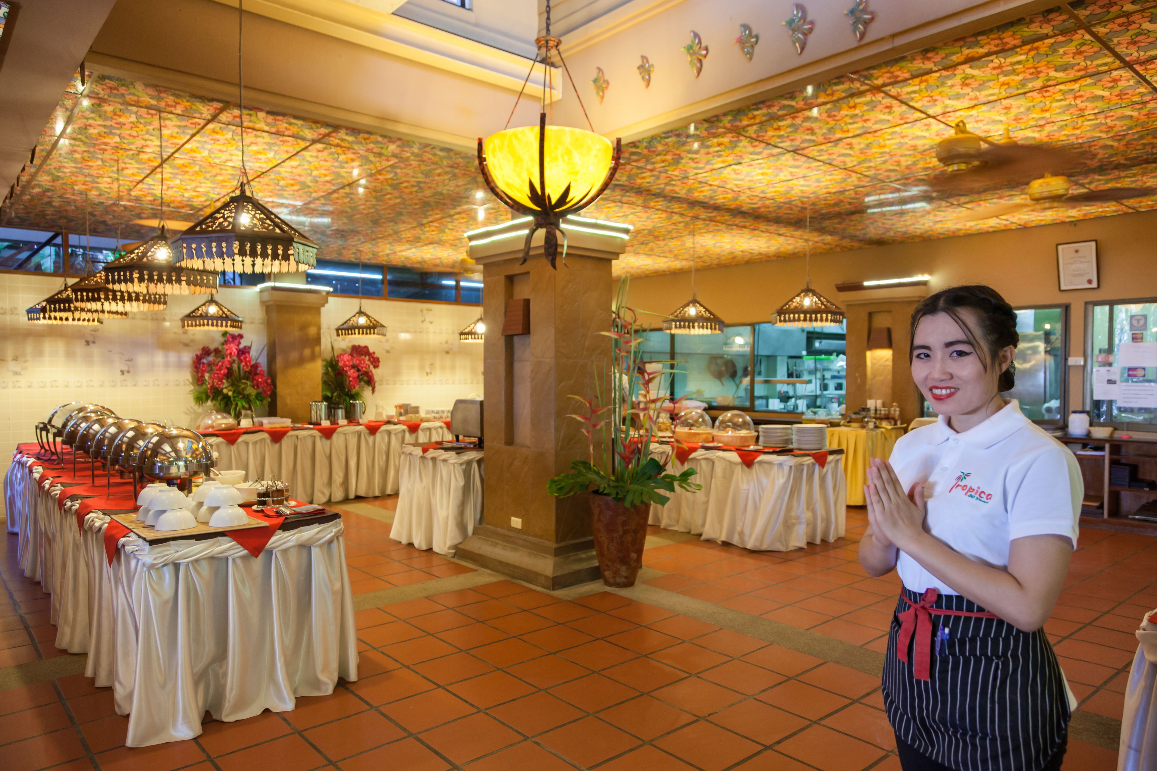 A banquet hall with tables set for a formal event, a central column, and hanging chandeliers.