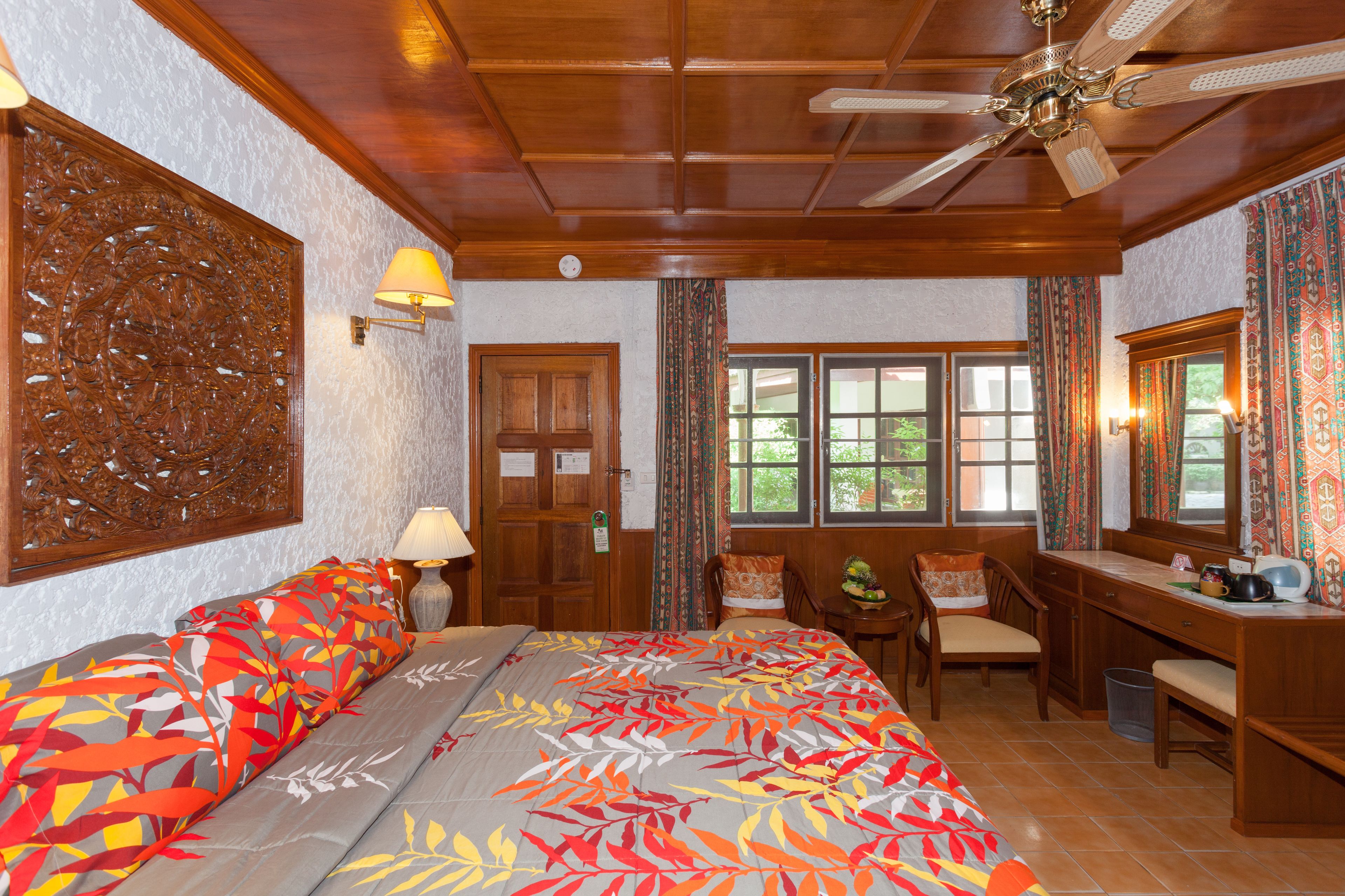 A hotel room with a bed, desk, chairs, and a window with curtains.