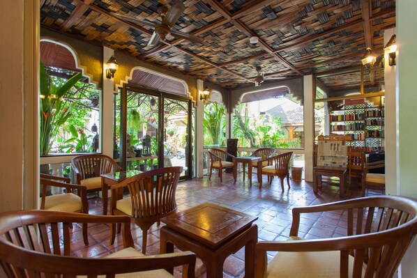 A covered outdoor seating area with wooden furniture and a ceiling made of books. - Tropica Bungalow Resort (Patong)