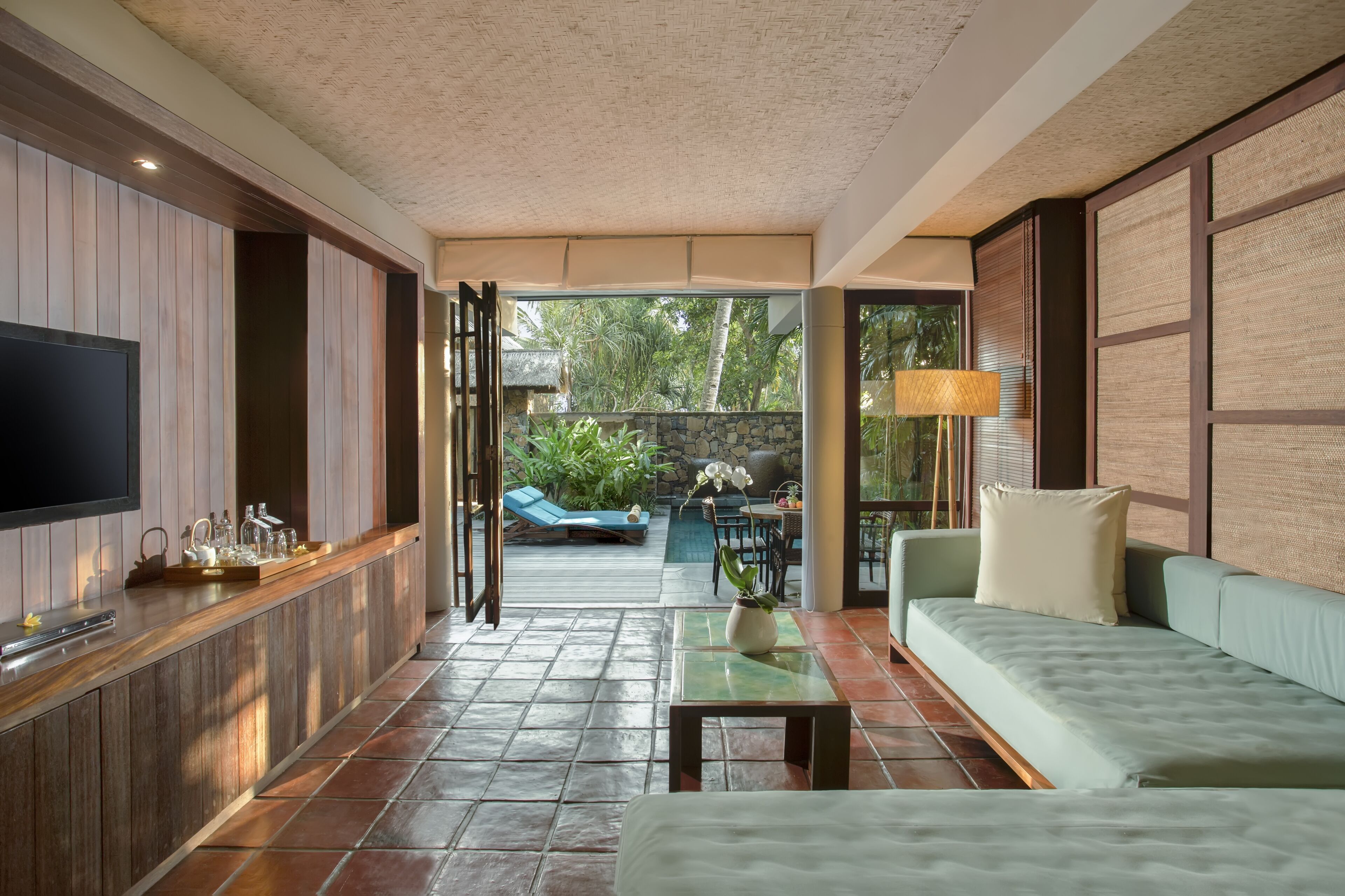 A modern living room with a TV, seating area, and a view of the outdoor patio.