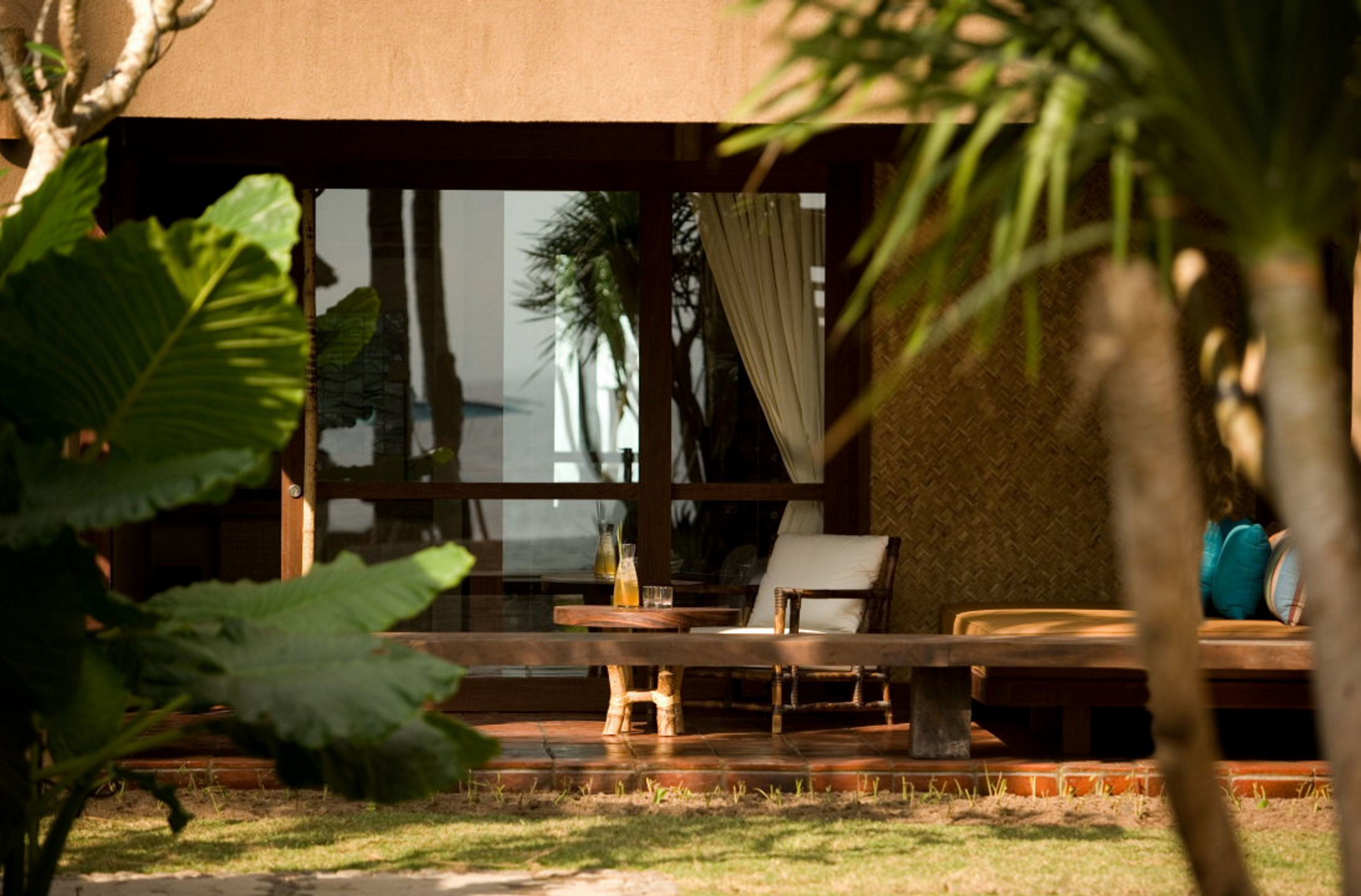 Una terraza de madera con una mesa y sillas, un ventanal y vista a un edificio.