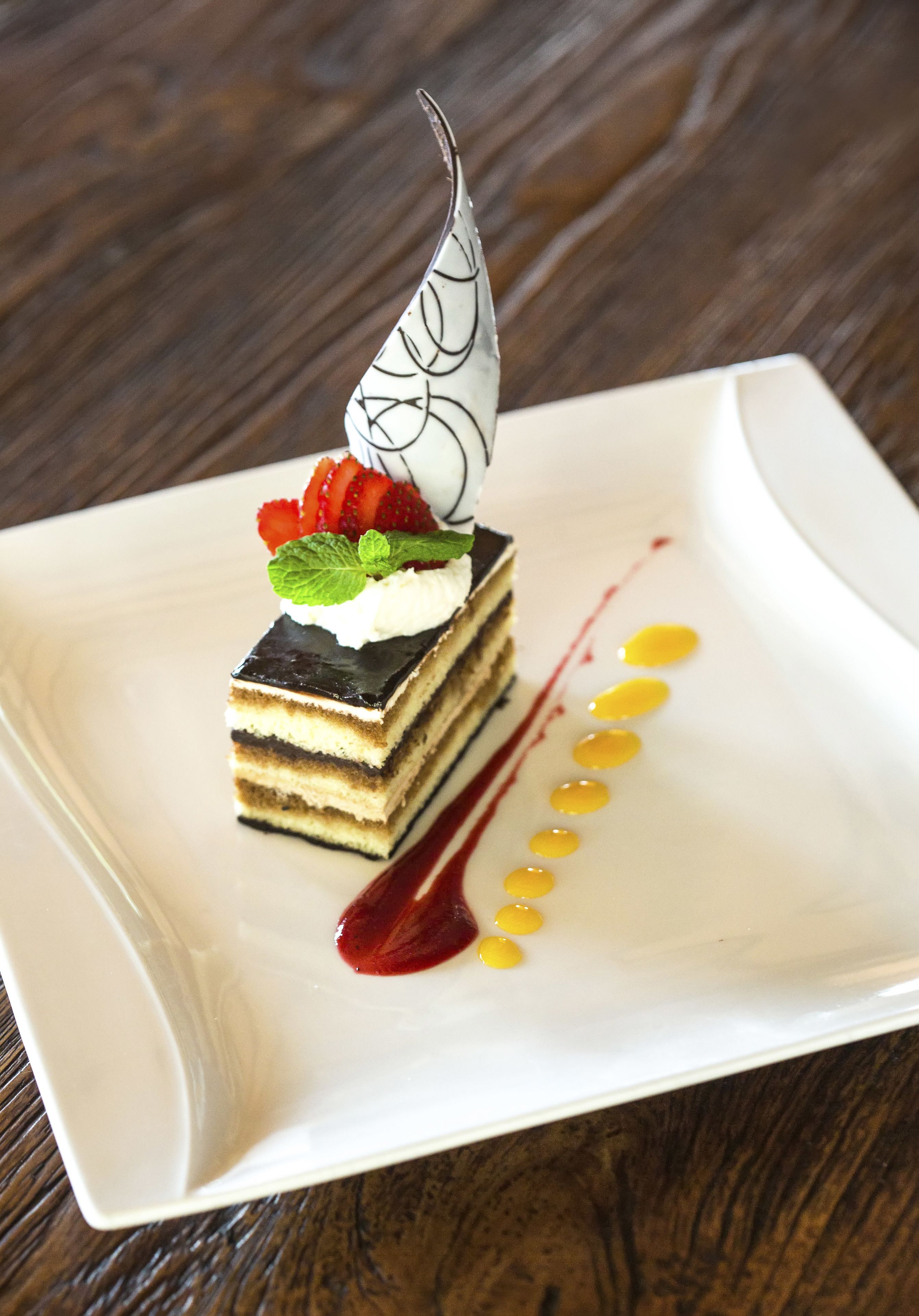 A dessert on a white square plate with a wooden table background.