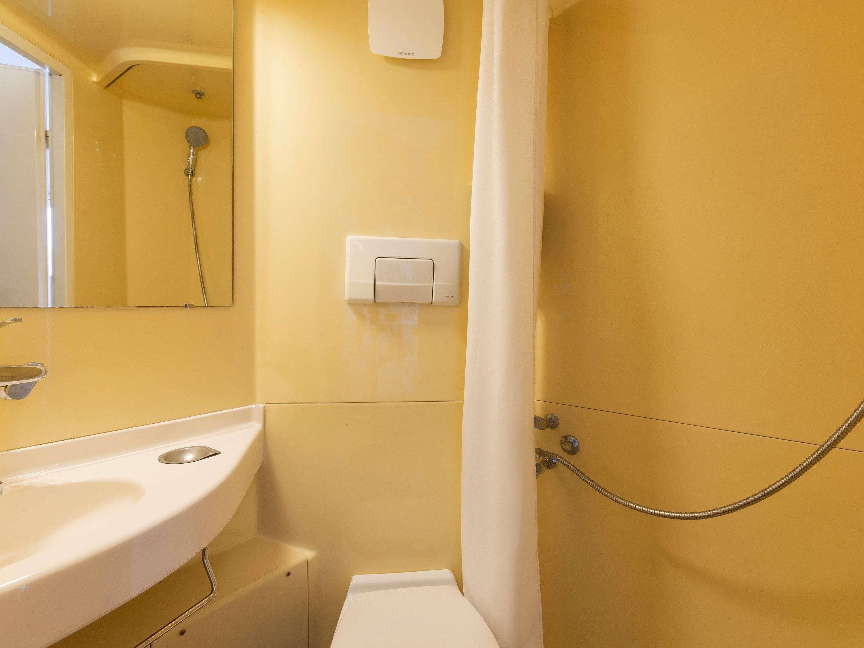 Een badkamer met een wastafel, spiegel, douche en een handdoekhouder.