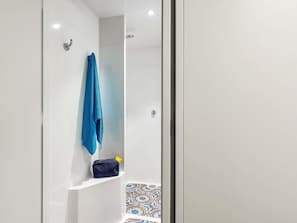 A bathroom with a shower, a towel rack, and a small shelf with a bag. - hotelF1 Nemours (Nemours)