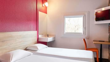 Een hotelkamer met een bed, een raam, een wastafel en een stoel.