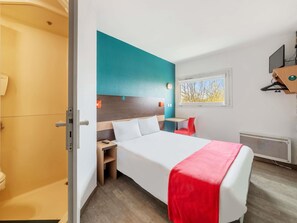 A hotel room with a bed, a desk, a chair, a window, and a radiator. - hotelF1 Nemours (Nemours)