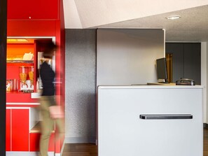 A modern interior with a red counter, a white reception desk, and a textured grey wall. - hotelF1 Nemours (Nemours)