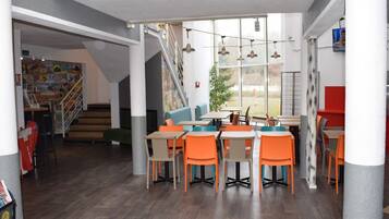 A modern interior with wooden flooring, orange and blue seating, and a staircase leading to another level.