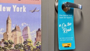 A hotel room door with a blue tag that reads "On the Road" and "NE PAS DÉRANGER DO NOT DISTURB" in French, indicating a hotel service. - hotelF1 Nemours (Nemours)