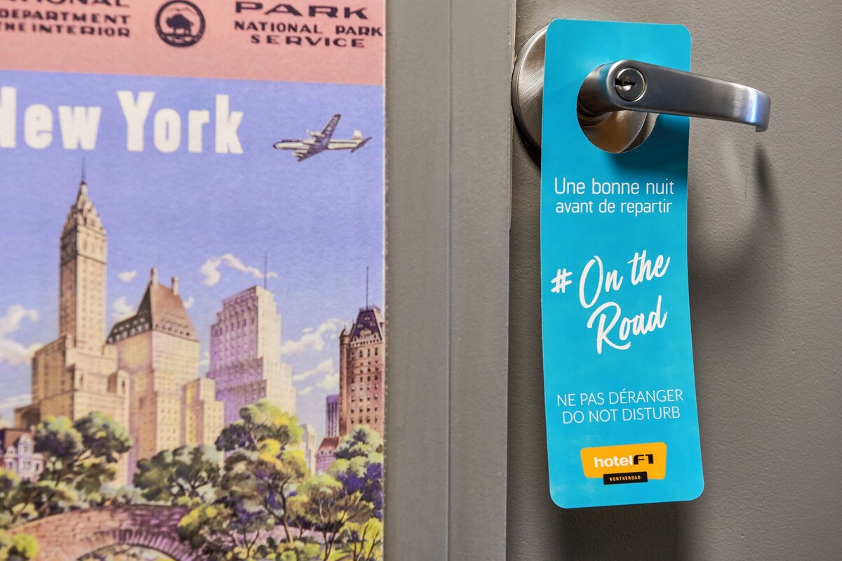 A hotel room door with a blue tag that reads "On the Road" and "NE PAS DÉRANGER DO NOT DISTURB" in French, indicating a hotel service.