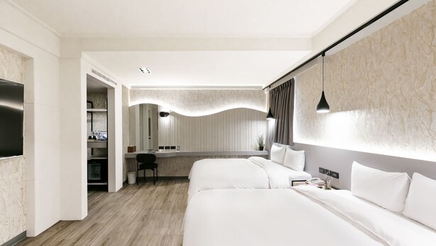 Ett modernt hotellrum med två sängar, ett skrivbord och en sittgrupp.