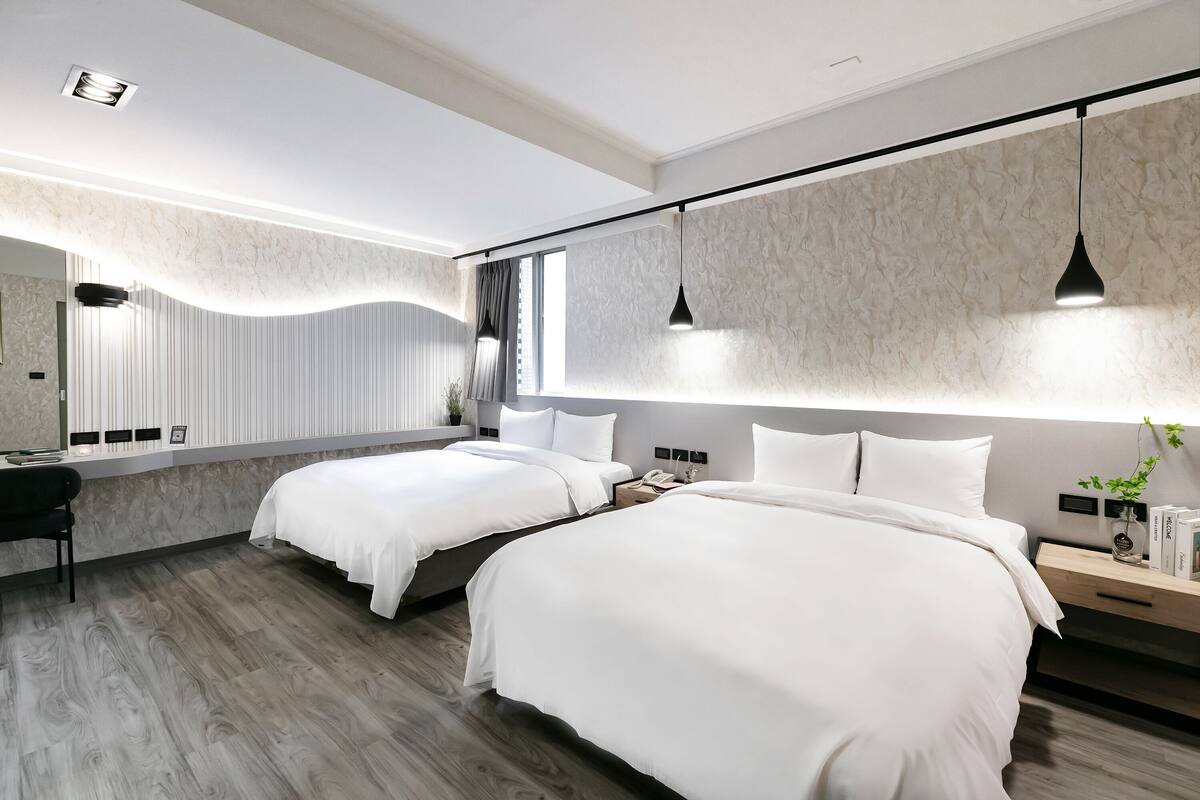 A modern hotel room with two beds, a desk, and a large mirror.