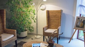 A cozy room with wicker furniture, a potted plant, and a small table with a tablet and books. - Hôtel du Parc (Limoges)