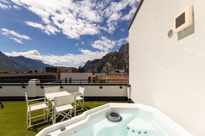 A rooftop terrace with a hot tub, outdoor seating, and a view of mountains. - Hi Hotels Riva del Garda (Riva del Garda)