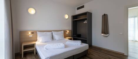 Een moderne hotelkamer met een groot bed, nachtkastjes, een ingebouwde televisie en een kledingkast.