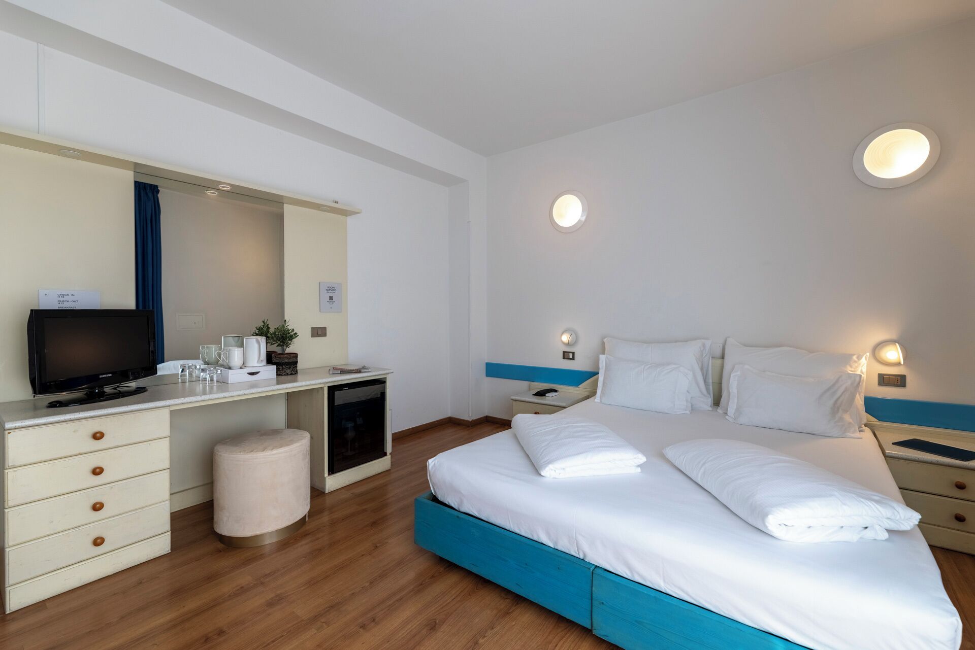 Une chambre d’hôtel comprenant un lit, un bureau avec une télévision, une petite kitchenette et une salle de bain.