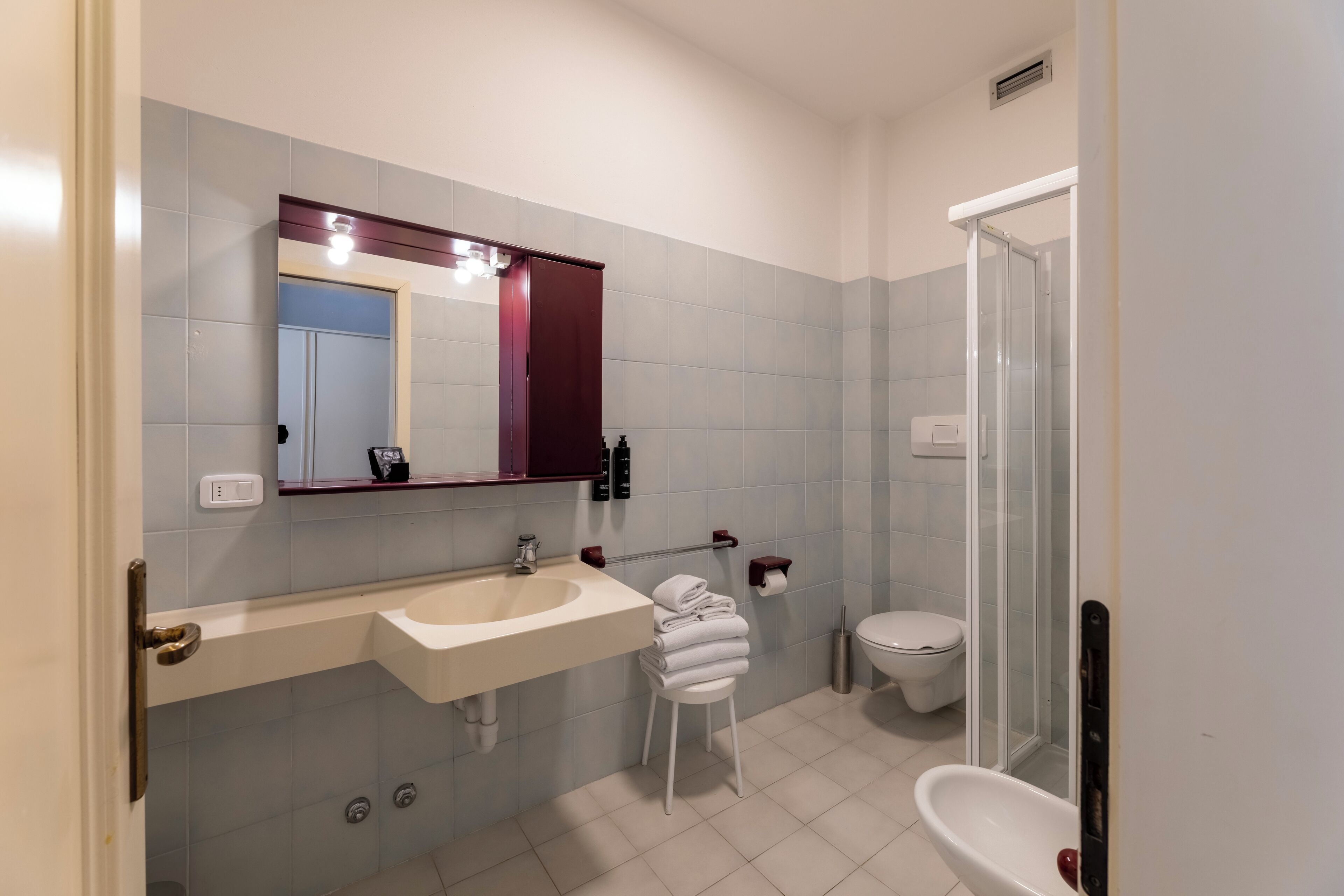 Een badkamer met een wastafel, spiegel, toilet en douche.