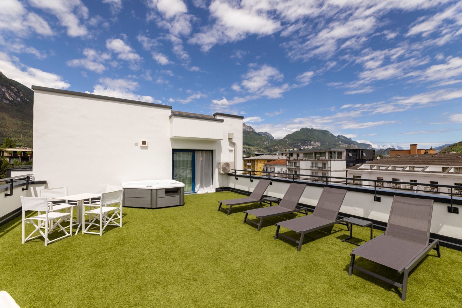 A rooftop terrace with a hot tub, lounge chairs, and a table.