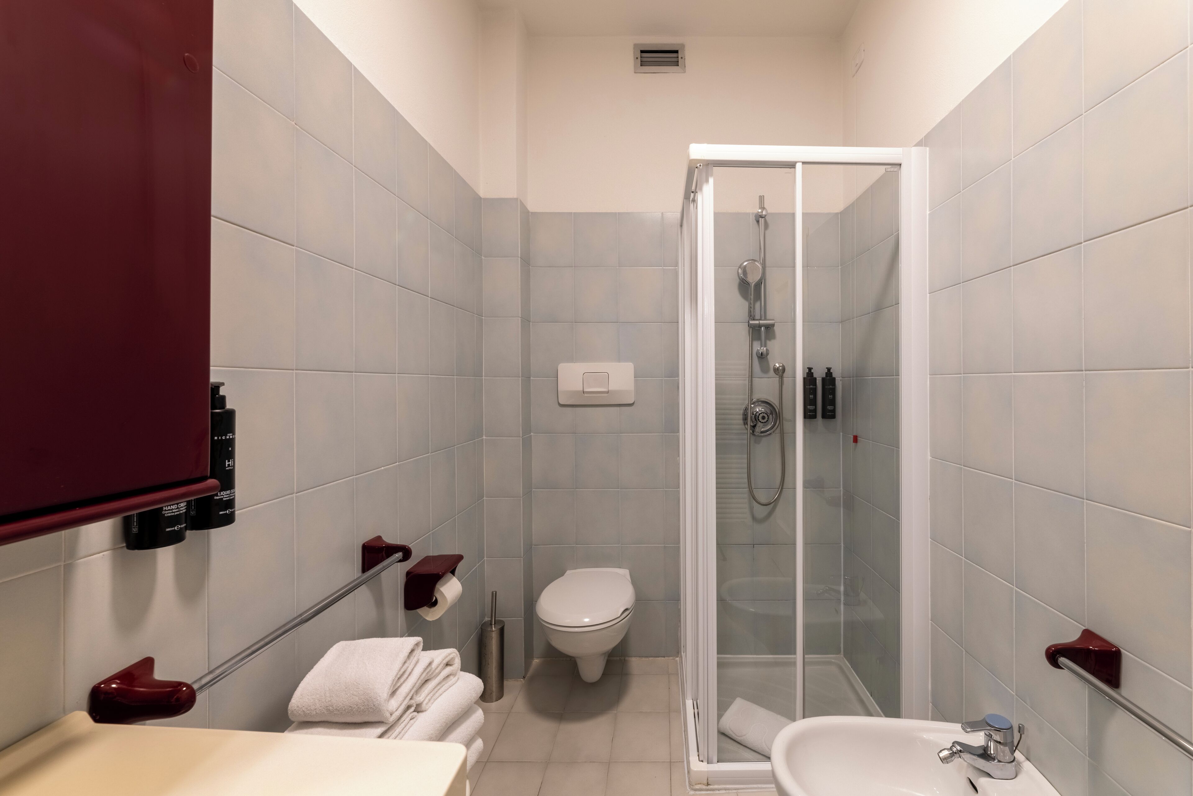 A bathroom with a glass-enclosed shower, a toilet, and a sink.