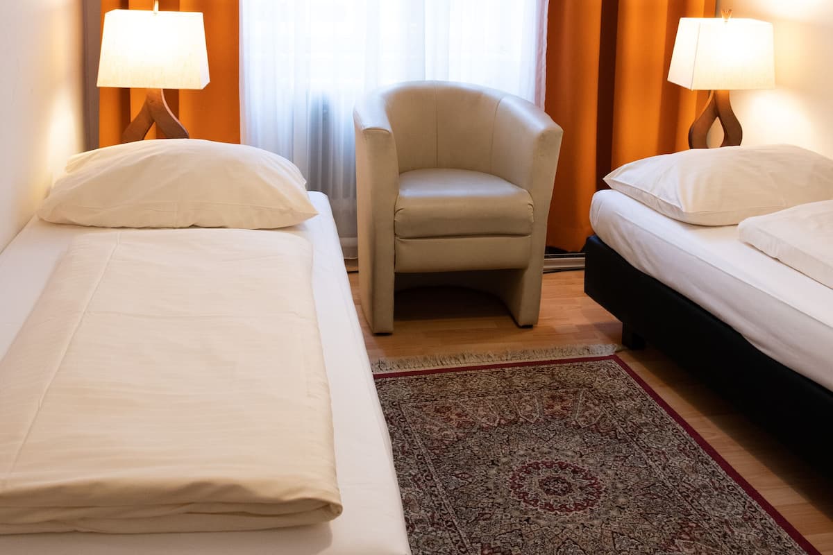 Habitación de hotel con dos camas, una silla y una alfombra.