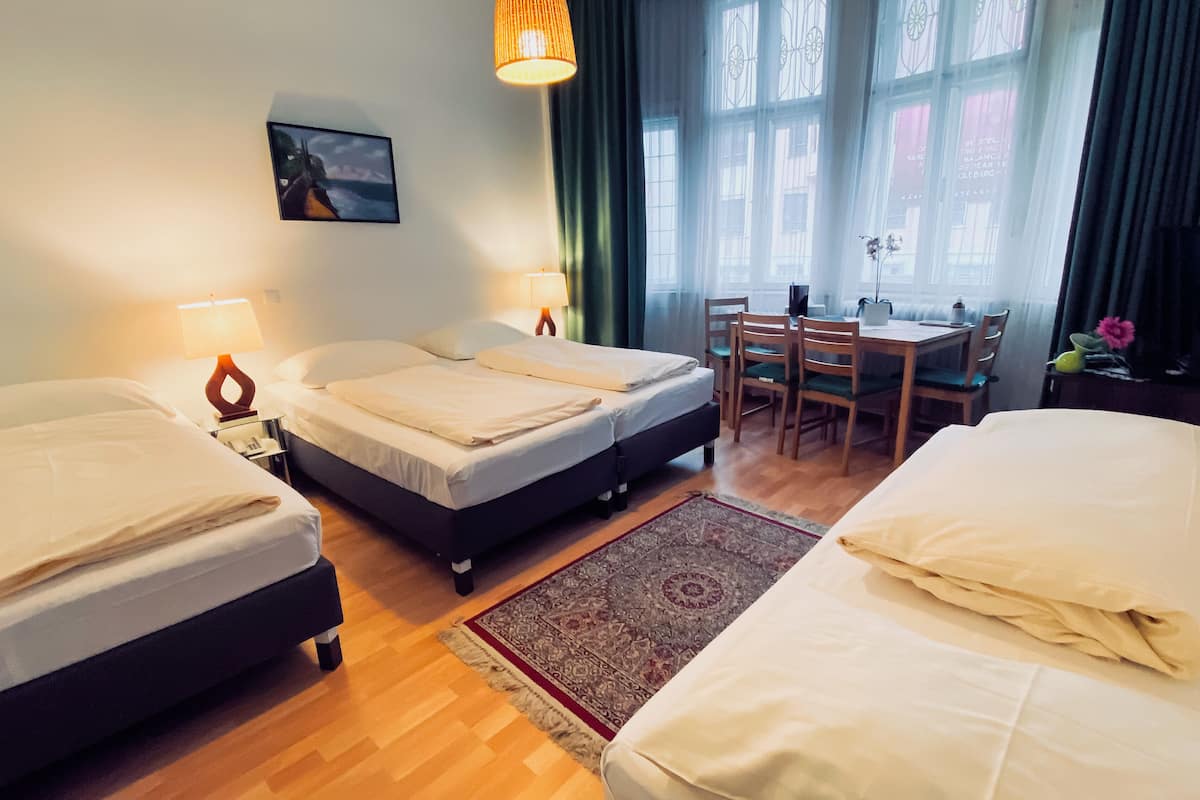 Habitación de hotel con dos camas, un escritorio y una silla. Hay un cuadro en la pared y una ventana con cortinas.