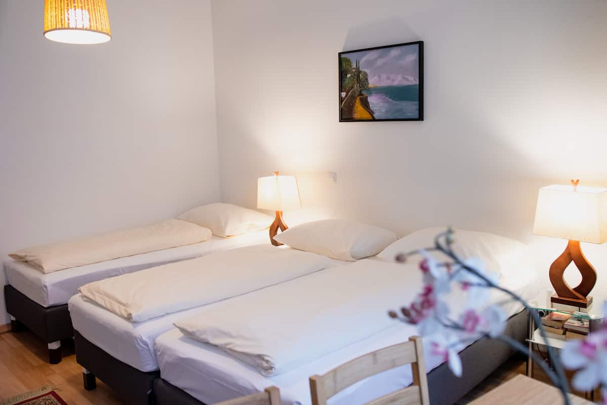 Habitación de hotel con dos camas, una mesita de noche, una lámpara y un cuadro en la pared.
