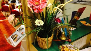 Un comptoir d’accueil agrémenté d’une plante en pot, d’une cloche décorative et d’un bol de chocolats.