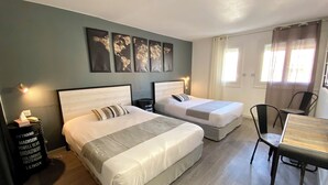 A hotel room with two beds, a desk, and a chair. There are wall-mounted lights and a window with curtains.