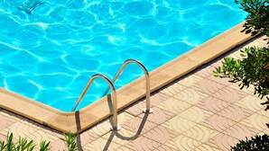 A swimming pool with clear blue water and a tiled deck.