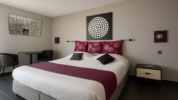 A hotel room with a large bed, a desk, and chairs.