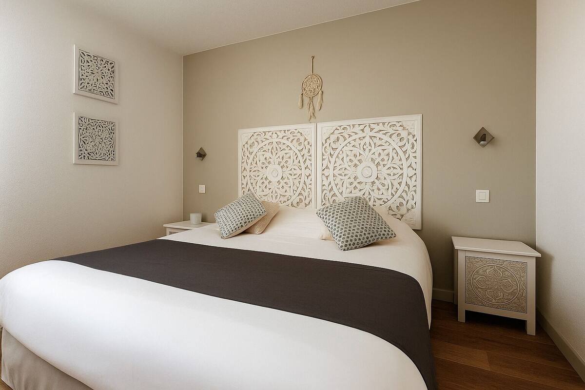 Une chambre à coucher avec un lit, des tables de chevet, des panneaux décoratifs et un attrape-rêves.